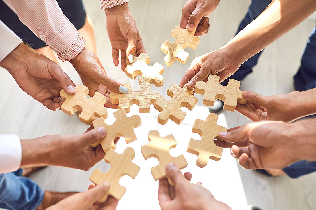 Company employees playing game and joining pieces of jigsaw puzz