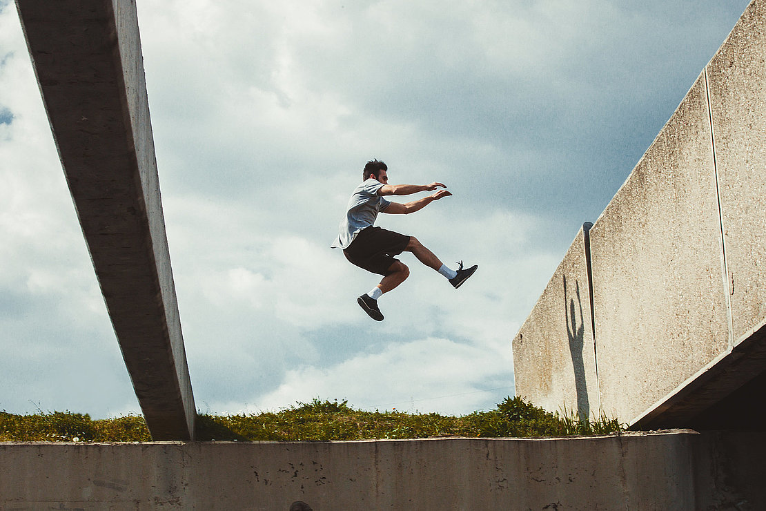 young man doing parkour jump in the city