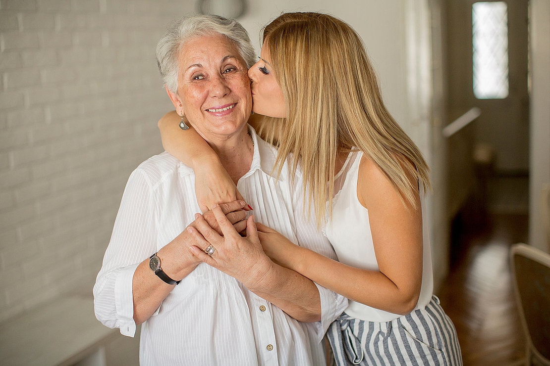 Granddaughter kissing grandmother in the room