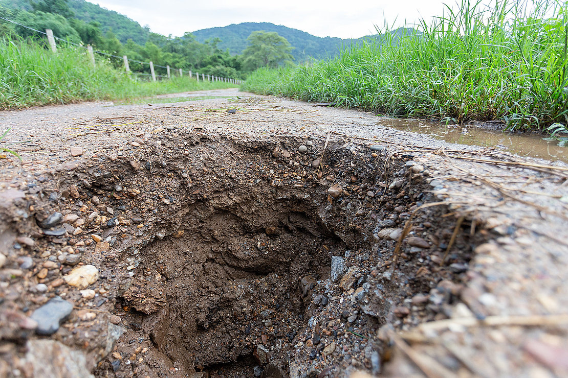 big hole on the ground country road due to broken pipes under the road See the dangers of traveling on broken paths. Roads are often damaged during the rainy season.