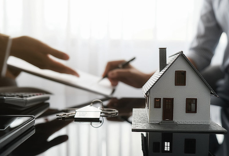 Real estate agent and customer signing contract to buy house, in