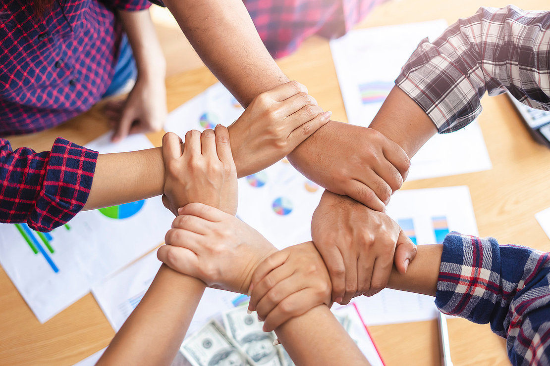 top view of employees standing around in a circle with their han
