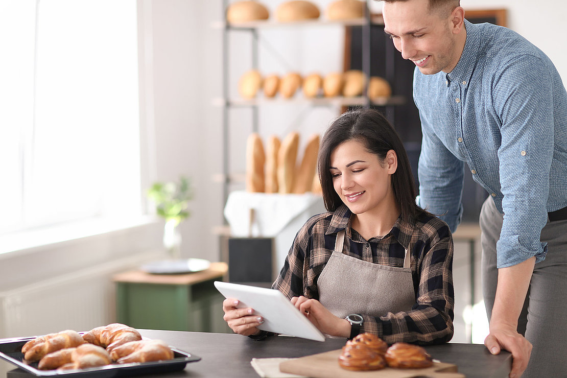 Young people using tablet computer in bakery. Small business owners