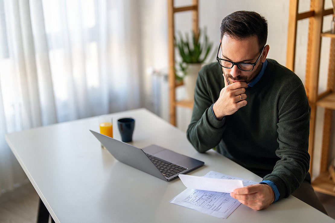 Satisfied man using laptop computer for electronic banking, making reservation, online shopping