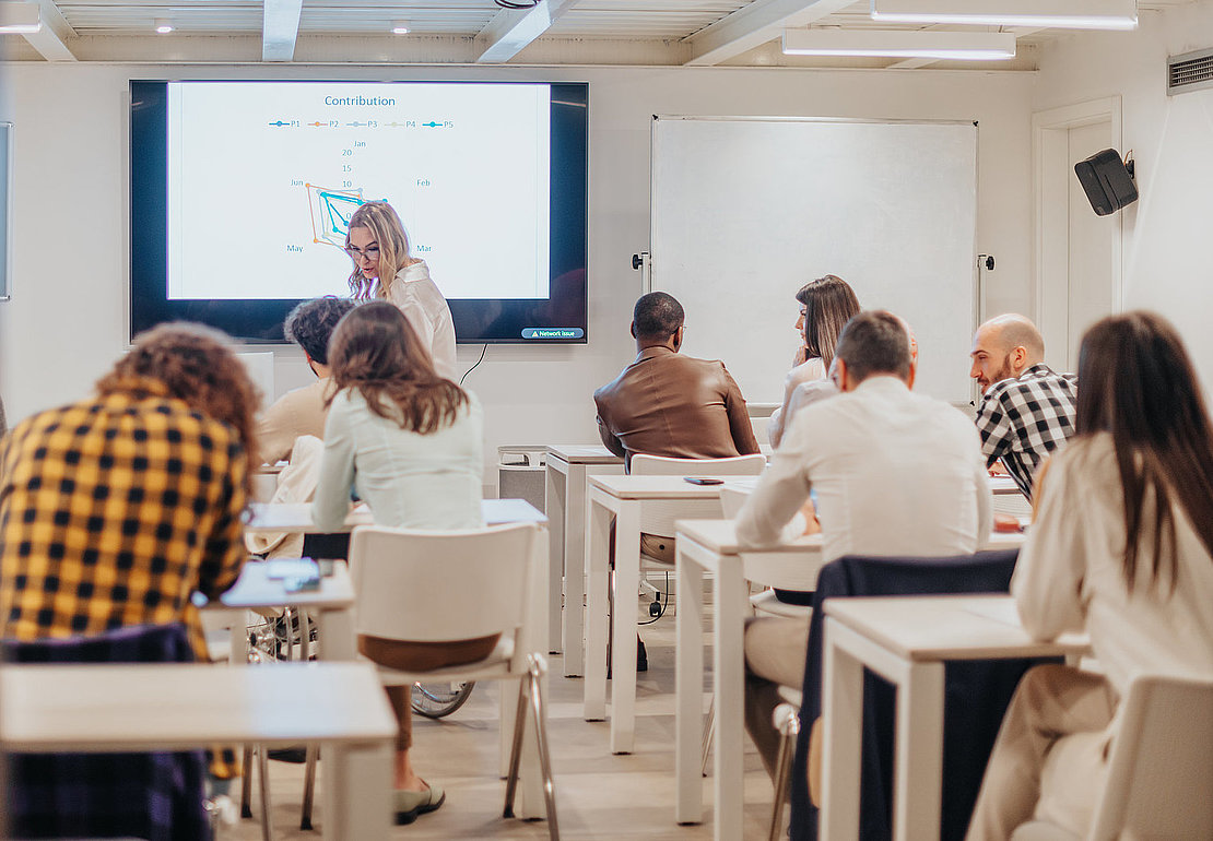 Diverse group of business people having training at the classroom by experienced middle-aged female business trainer