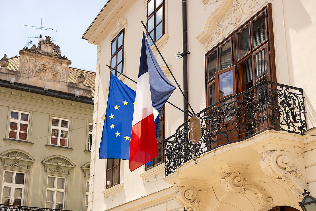 French and European Union flags fluttering together in the wind. Flags of France and the European Union on the building