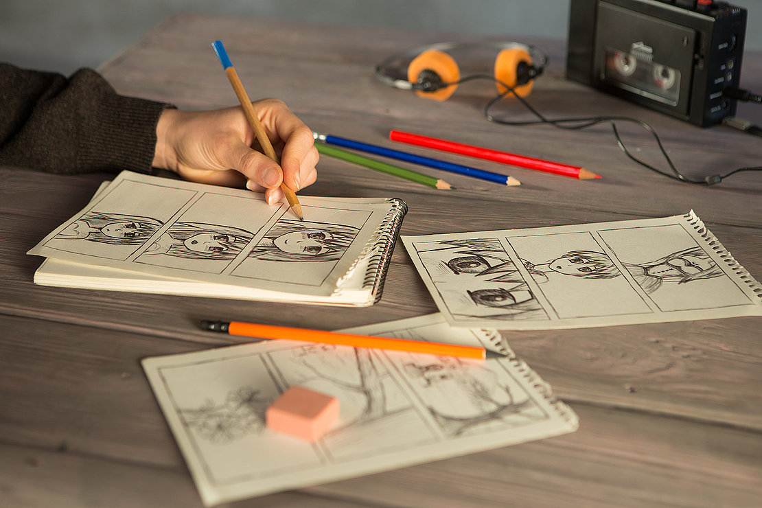 Artist drawing an anime comic book in a studio. Wooden desk, natural light. Creativity and inspiration concept.