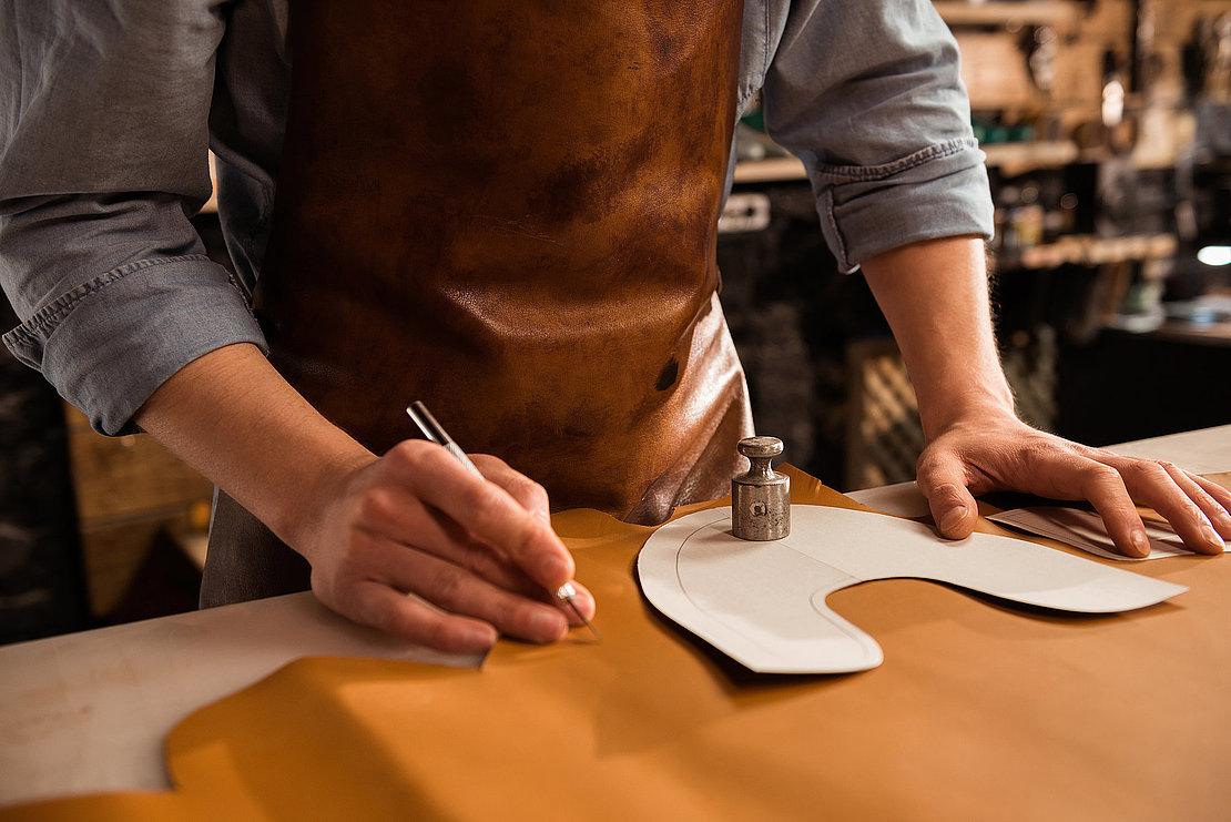 Close up of a male shoemaker cutting leather textile