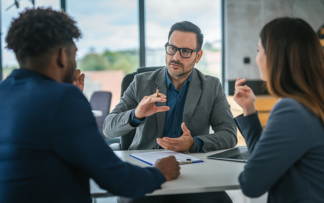 Financial adviser discussing contract with diverse couple in office meeting