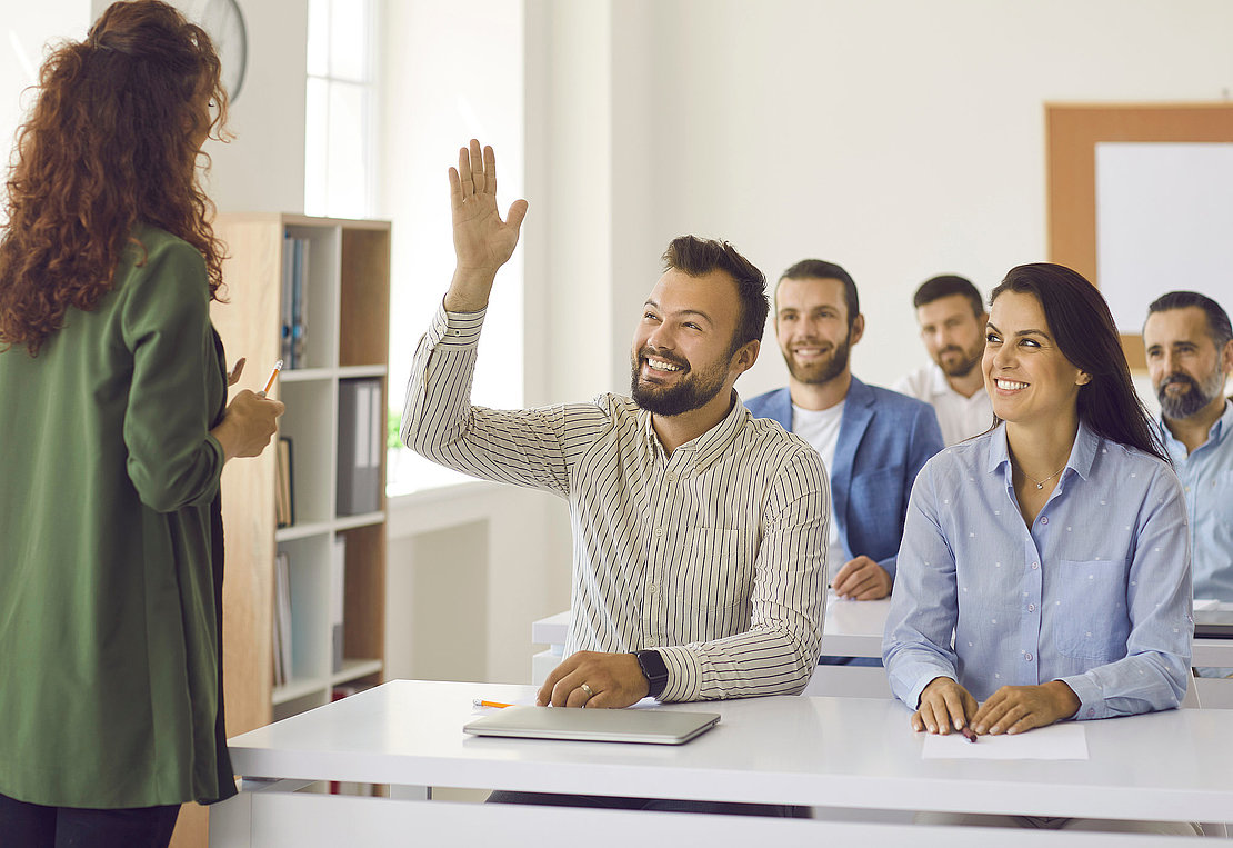Happy man raises hand to ask coach some questions during class o