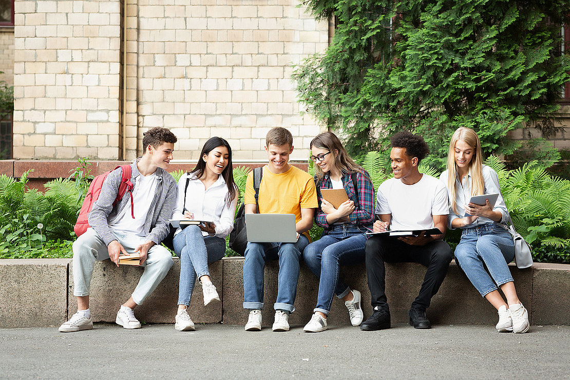 Students doing group project on laptop, sitting in university campus