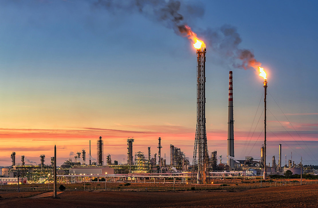 Sines refinery, Portugal at sunset with chimneys giving off flam