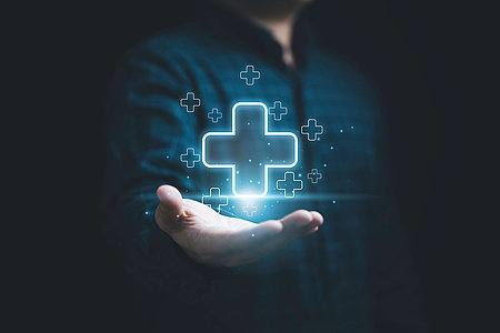 Businessman holding virtual blue plus sign for positive thinking