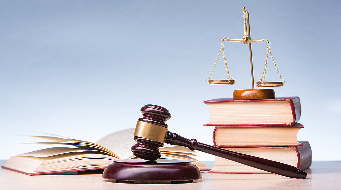 Legal Law and Justice concept - Open law book with a wooden judges gavel on table in a courtroom or law enforcement office. Copy space for text.